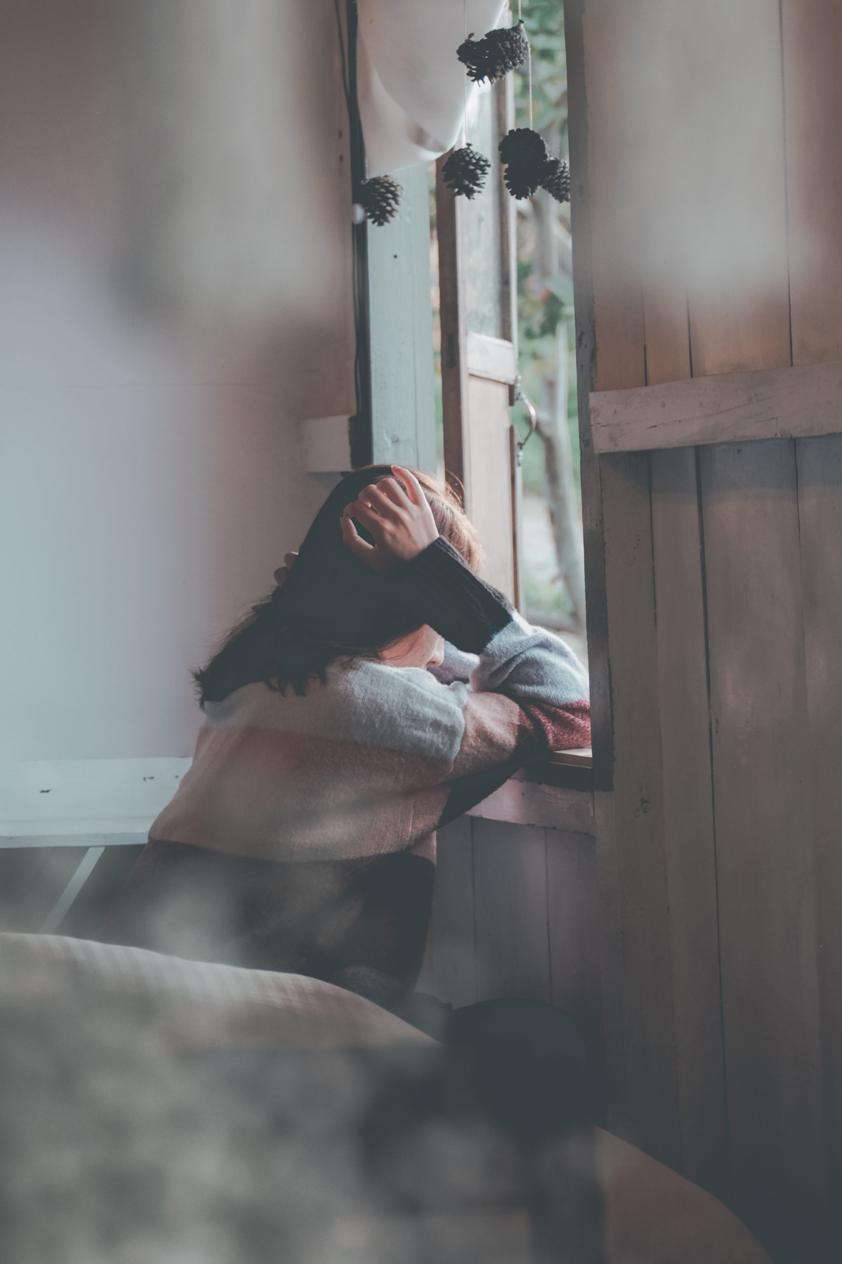 Person leaning on a wooden window grieving